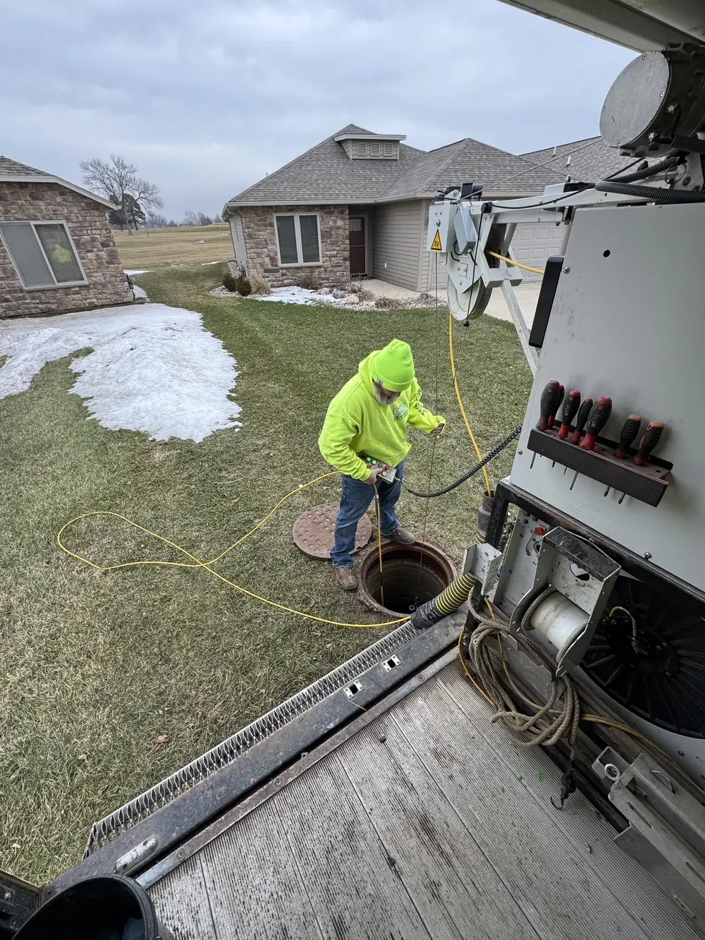 A CIT technician operates equipment at an open manhole.