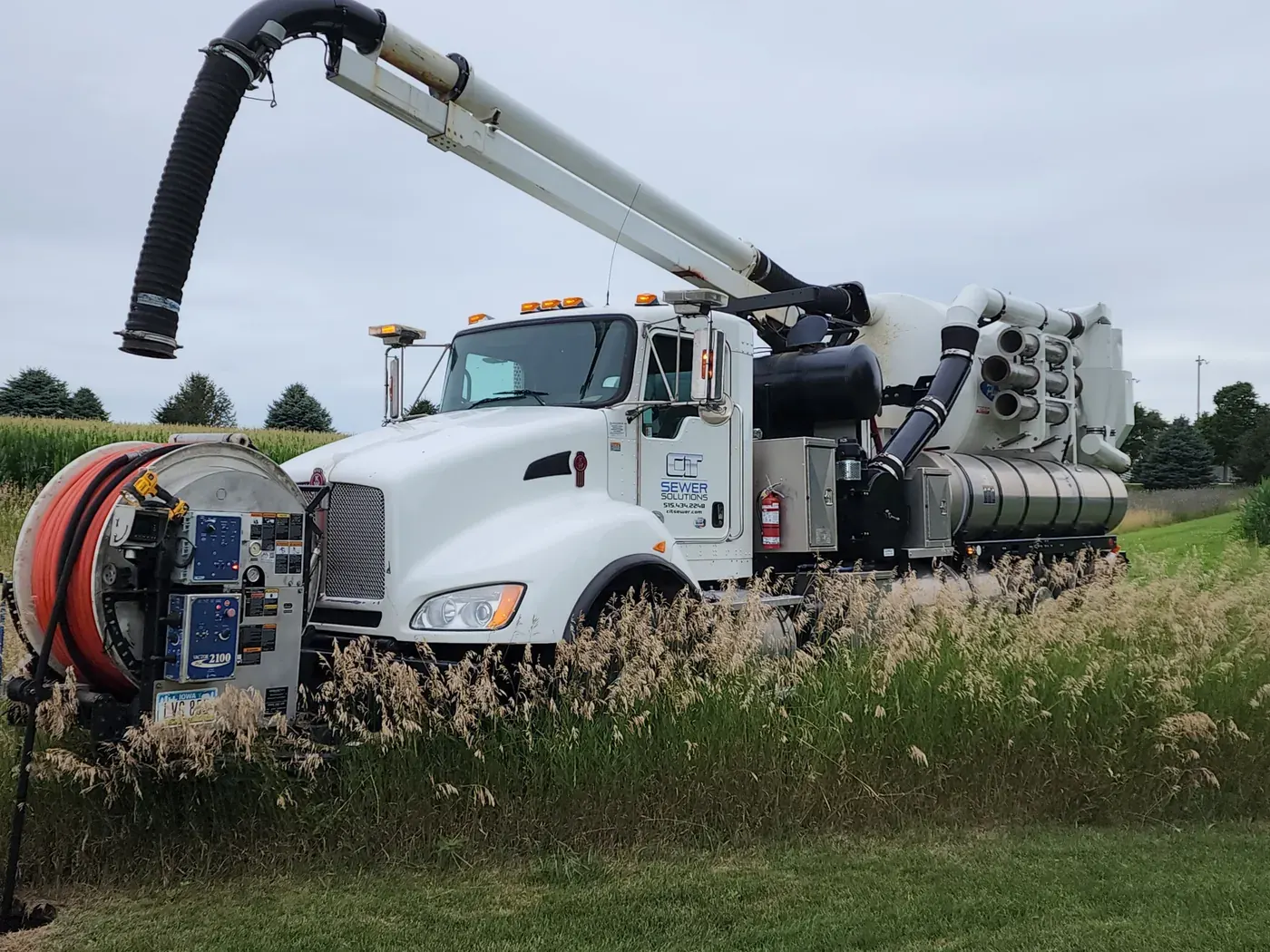 A CIT combination truck positioned in the field with its vacuum boom extended.