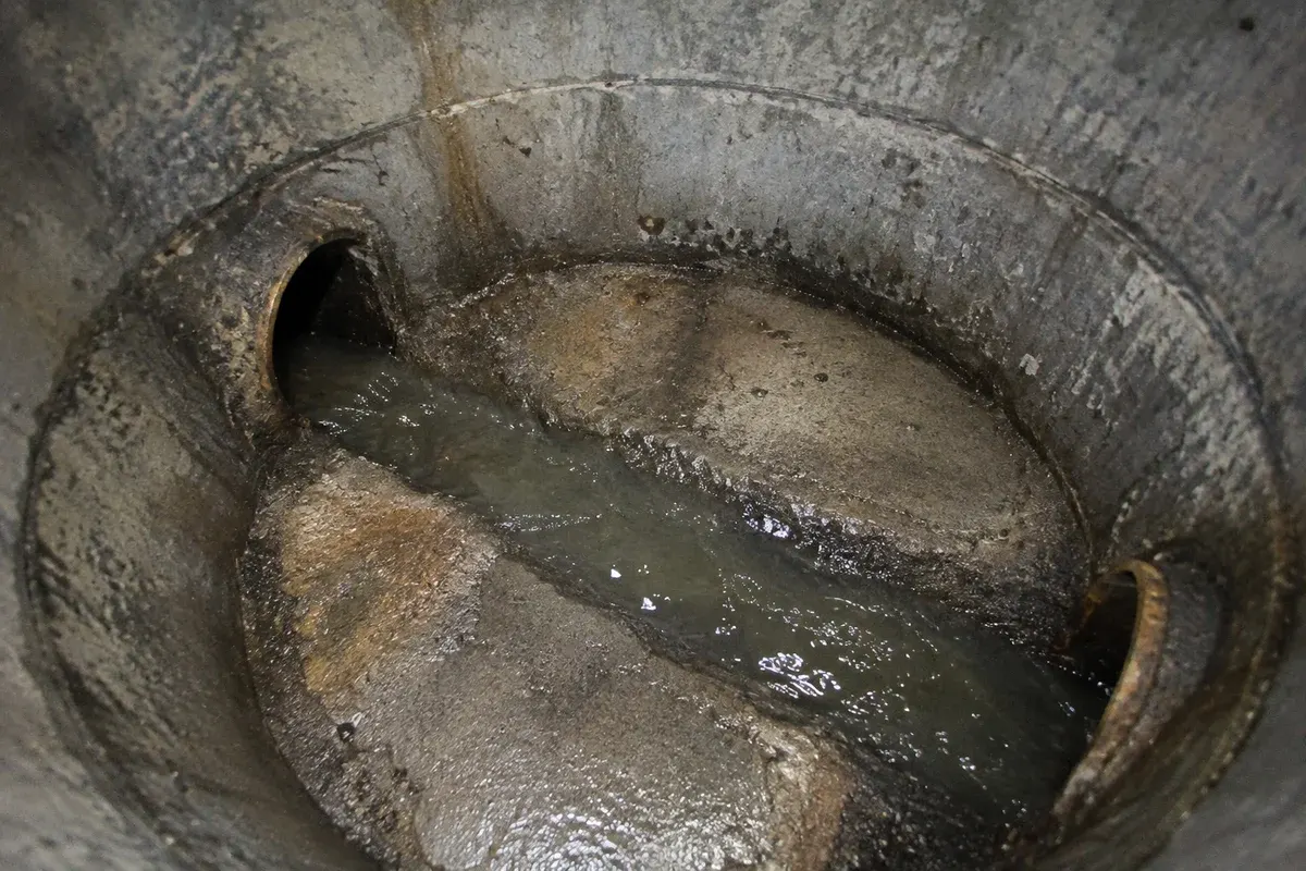Condition illustration of a concrete manhole with two pipe connections and a formed drainage channel.