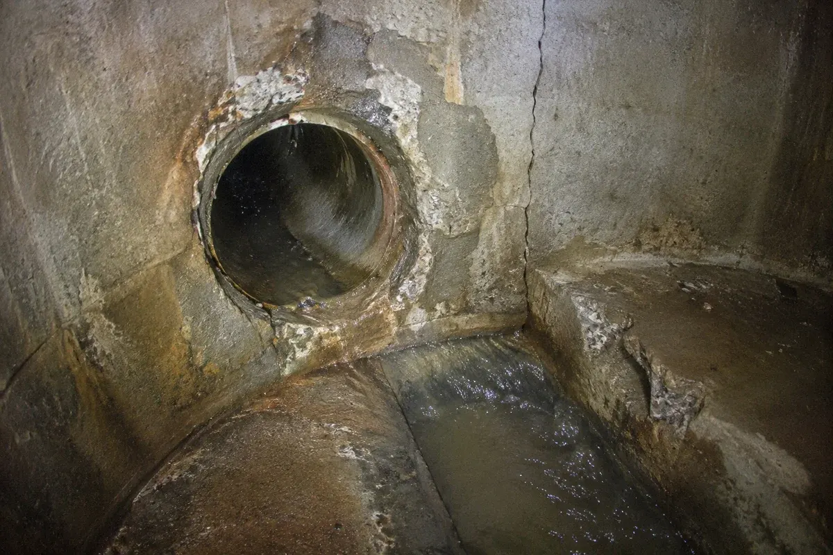 Condition illustration showing a manhole pipe connection, cracked bench and deteriorated wall for rehabilitation review.