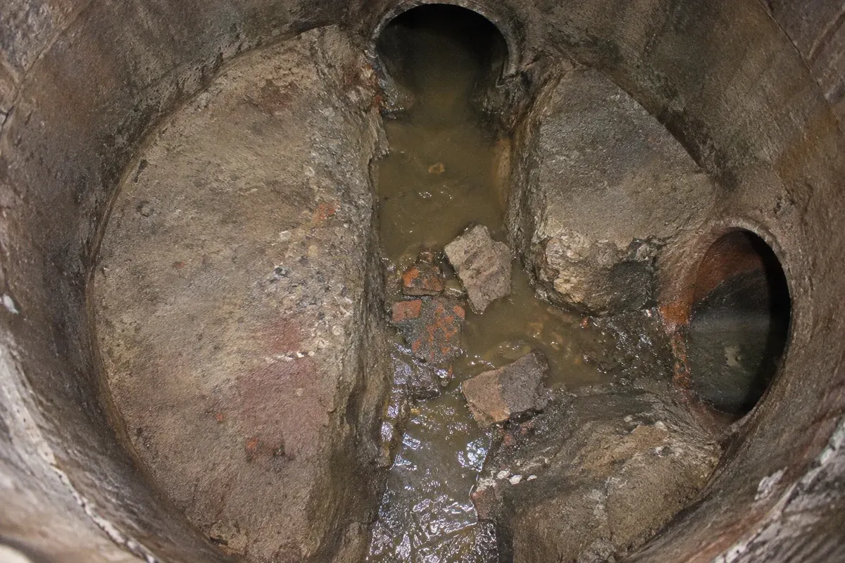 Condition illustration of sediment and loose masonry restricting a manhole flow channel.